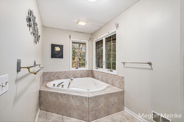 bathroom featuring tile patterned flooring, a textured ceiling, and a relaxing tiled tub