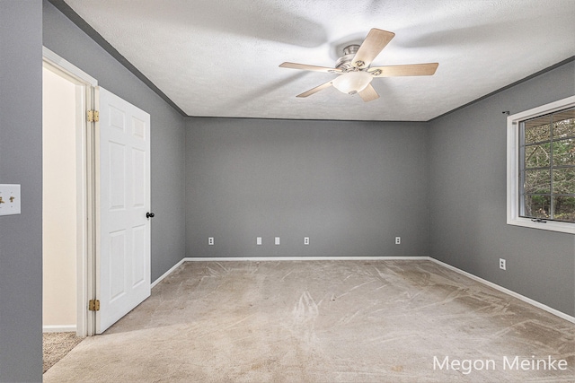 spare room with a textured ceiling, light carpet, and ceiling fan