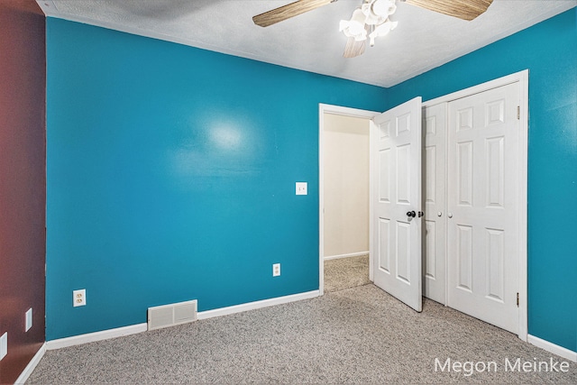 unfurnished bedroom featuring a textured ceiling, light colored carpet, ceiling fan, and a closet