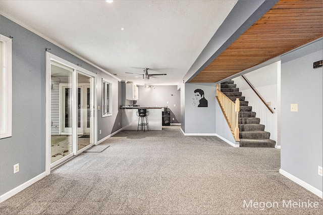 interior space featuring ceiling fan, wood ceiling, carpet flooring, and crown molding