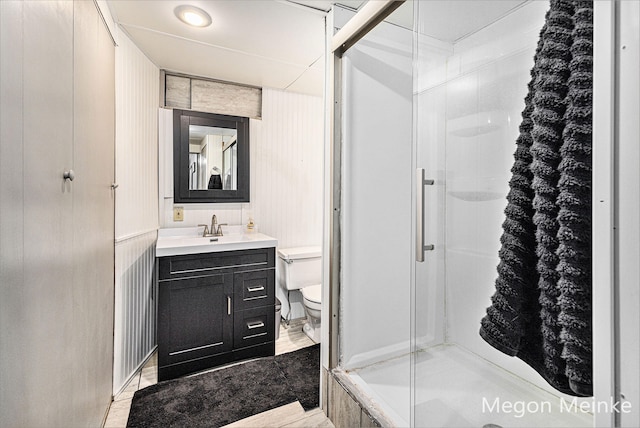 bathroom with walk in shower, vanity, and toilet