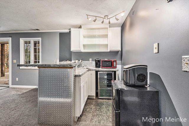 kitchen featuring wine cooler, a textured ceiling, dark colored carpet, and white cabinets