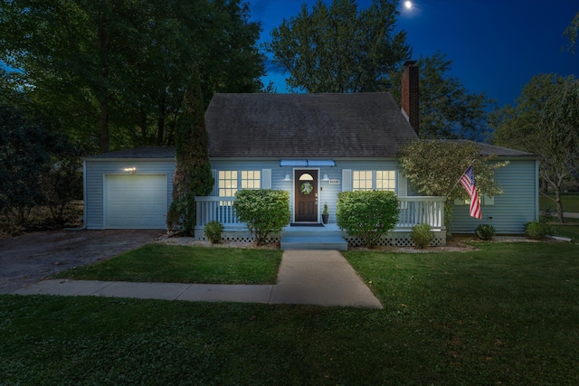 cape cod-style house featuring covered porch, a garage, and a front lawn