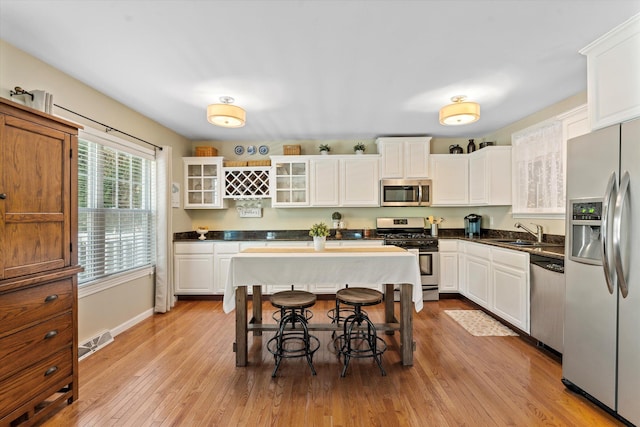 kitchen with white cabinets, appliances with stainless steel finishes, and light hardwood / wood-style flooring