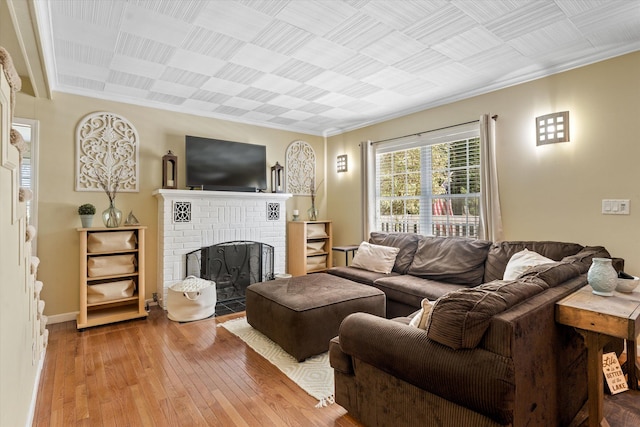 living room featuring wood-type flooring, ornamental molding, and a brick fireplace