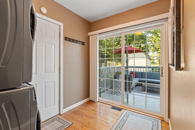 doorway to outside with light hardwood / wood-style floors and stacked washer / dryer