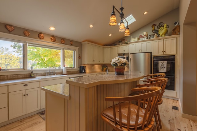 kitchen with pendant lighting, a center island, sink, light wood-type flooring, and a breakfast bar area