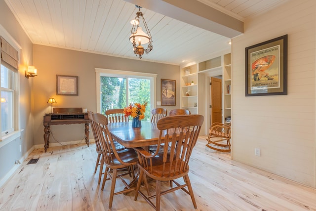 dining space with crown molding, built in features, and light wood-type flooring