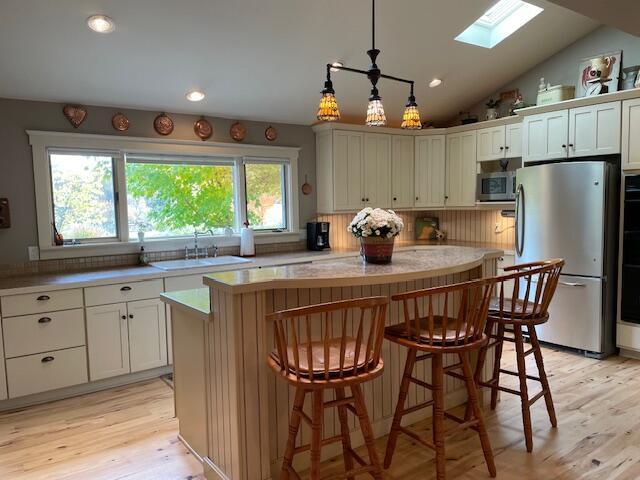 kitchen featuring appliances with stainless steel finishes, decorative light fixtures, plenty of natural light, a kitchen island, and decorative backsplash