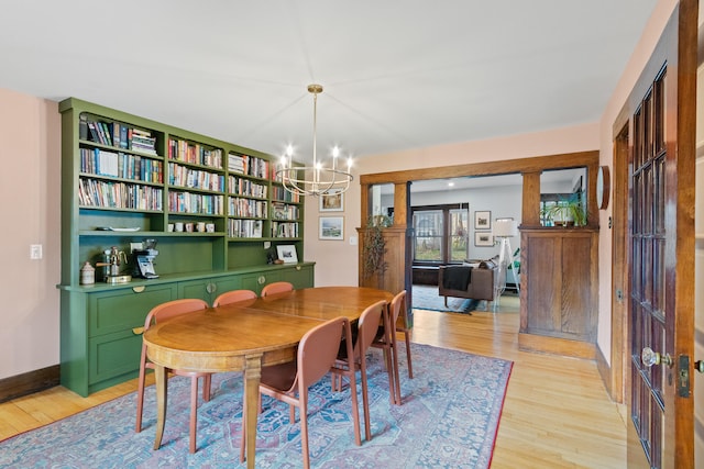 dining space with built in features, a chandelier, and light wood-type flooring