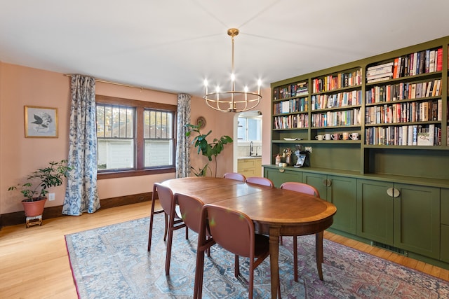 dining area featuring light wood-type flooring, sink, and an inviting chandelier