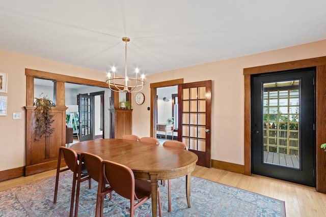 dining space with french doors, a chandelier, and light hardwood / wood-style floors