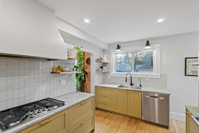 kitchen with tasteful backsplash, sink, light hardwood / wood-style floors, and appliances with stainless steel finishes