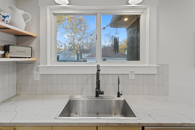 details featuring light stone countertops, backsplash, and sink