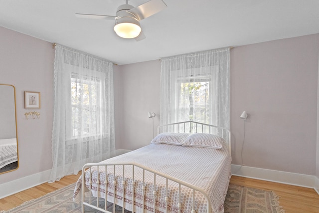 bedroom with multiple windows, hardwood / wood-style flooring, and ceiling fan