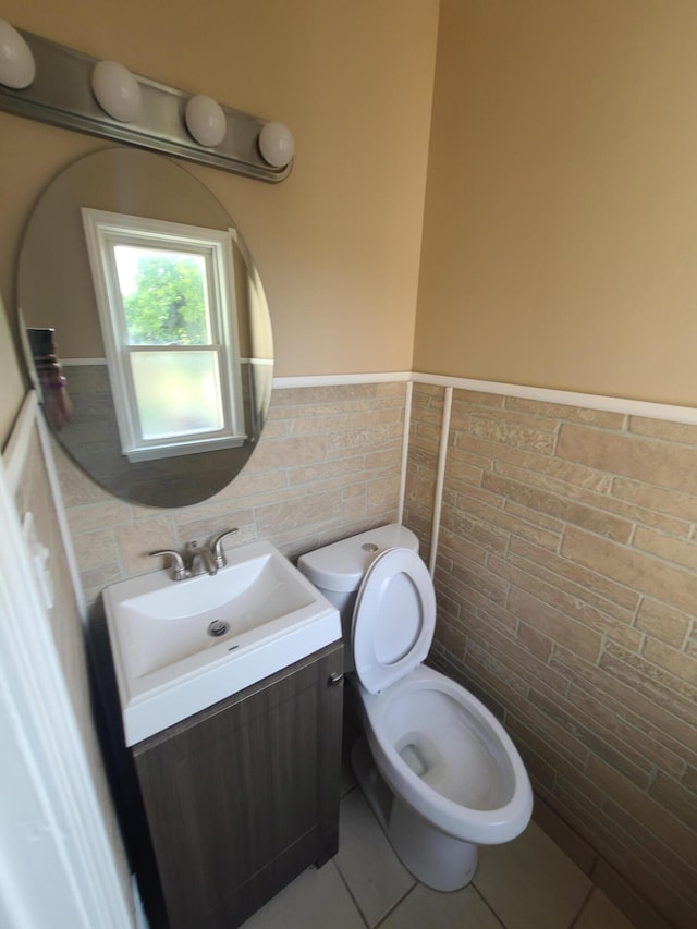 bathroom featuring tile patterned flooring, vanity, toilet, and tile walls