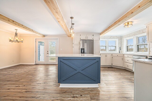 kitchen with stainless steel appliances, white cabinets, light countertops, beam ceiling, and decorative light fixtures