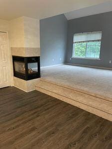 unfurnished living room with dark hardwood / wood-style flooring and a multi sided fireplace