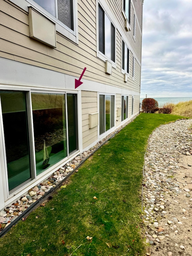 view of home's exterior featuring a water view and a lawn