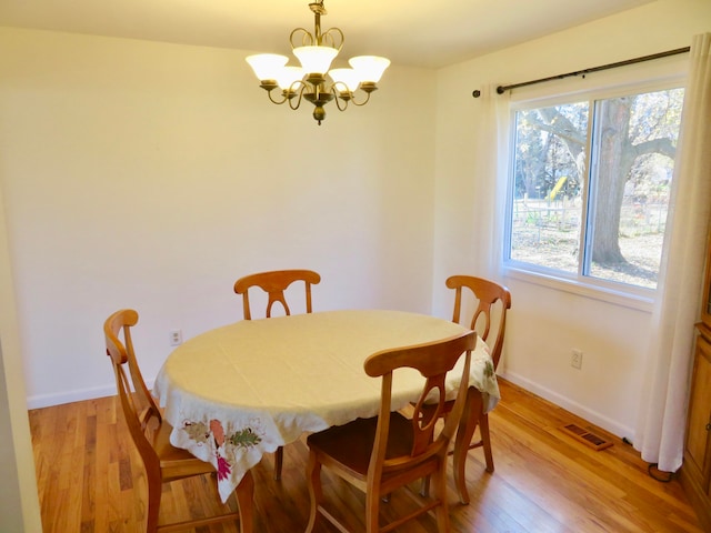 dining space with a chandelier and light hardwood / wood-style flooring