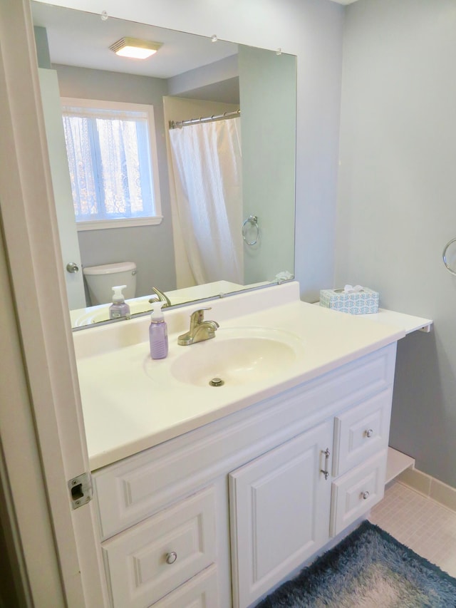 bathroom with toilet, vanity, and tile patterned floors