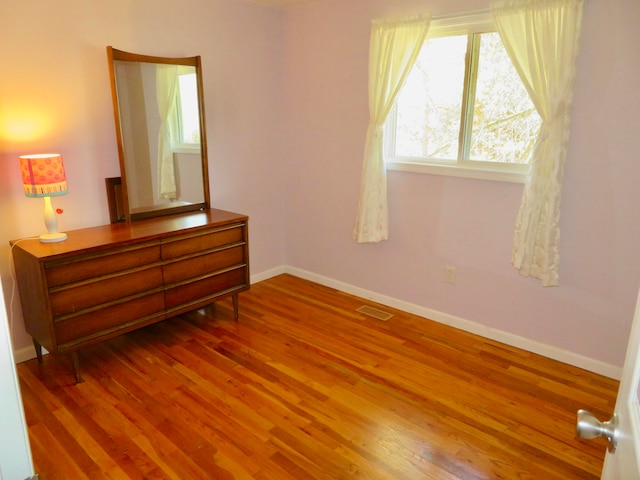 unfurnished bedroom featuring wood-type flooring and multiple windows