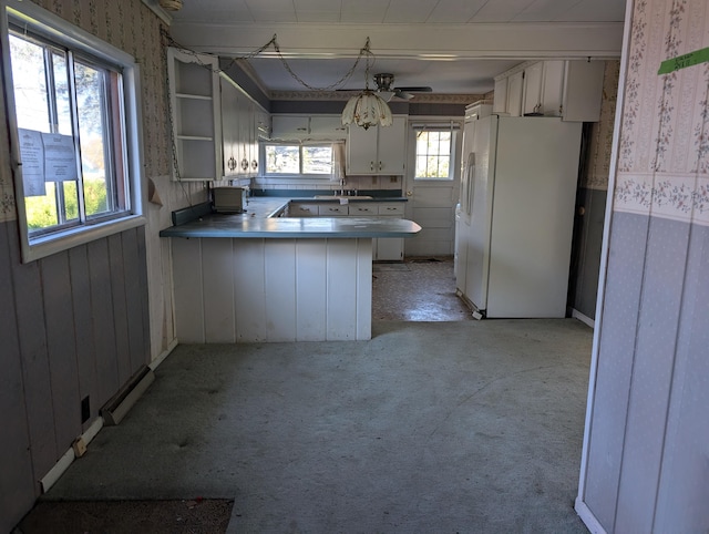 kitchen with white refrigerator with ice dispenser, white cabinetry, kitchen peninsula, light colored carpet, and ceiling fan