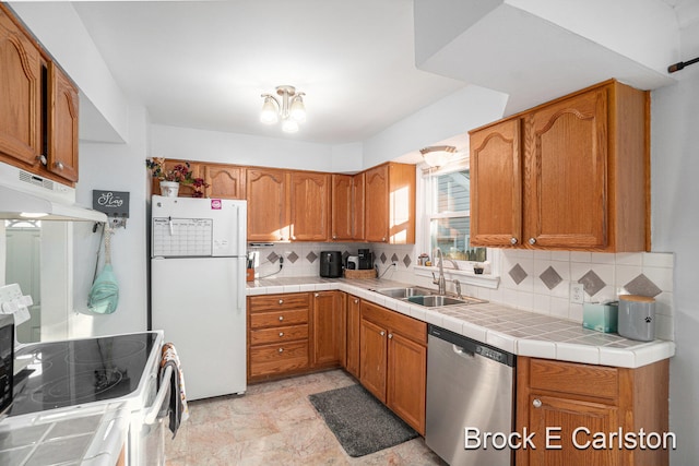 kitchen with tile countertops, white refrigerator, sink, stainless steel dishwasher, and backsplash