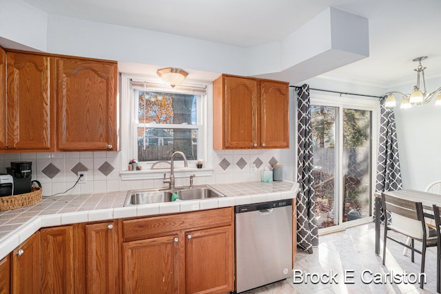 kitchen featuring tasteful backsplash, decorative light fixtures, sink, tile counters, and stainless steel dishwasher