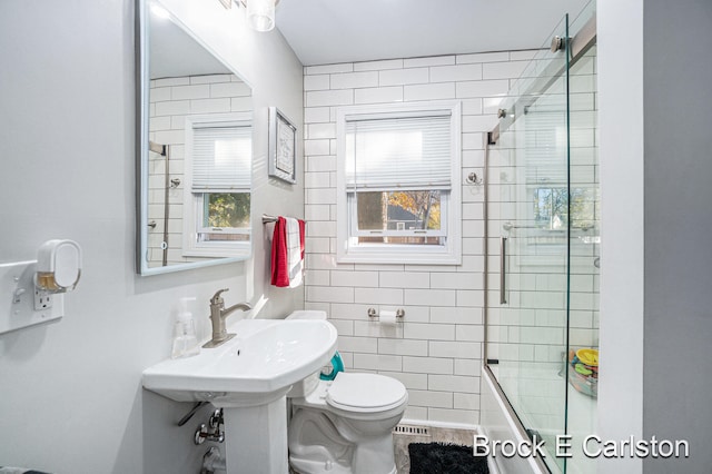 full bathroom with bath / shower combo with glass door, sink, and toilet