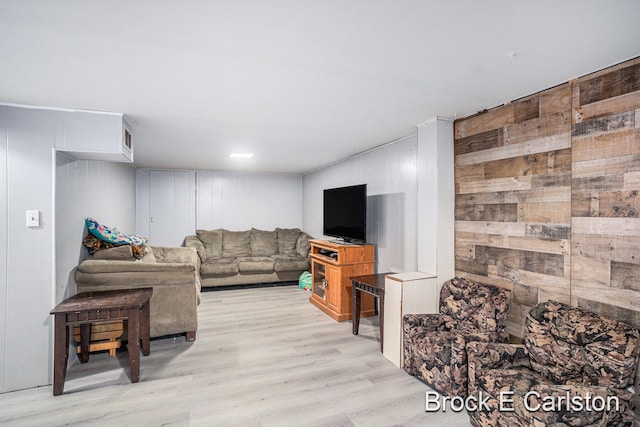 living room with light hardwood / wood-style floors and wood walls