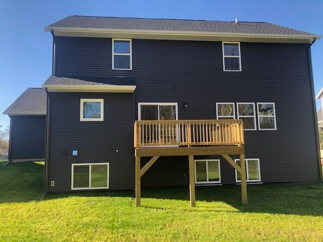 rear view of property featuring a lawn and a wooden deck