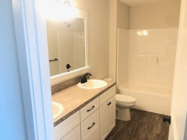 full bathroom with shower / washtub combination, vanity, wood-type flooring, and toilet