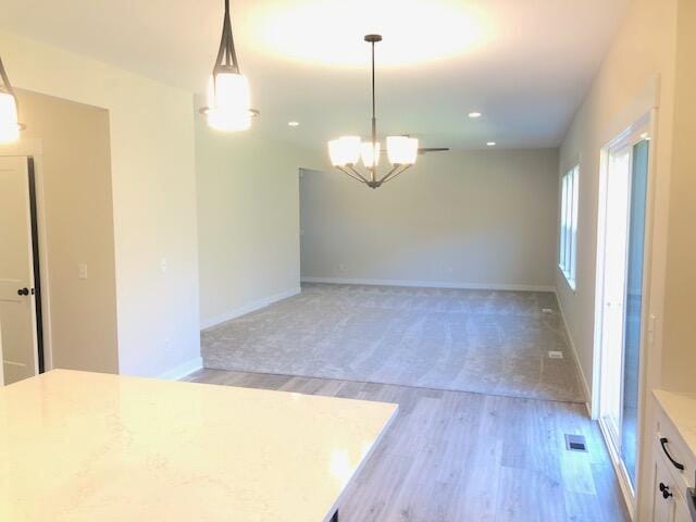 interior space featuring white cabinets, hardwood / wood-style flooring, hanging light fixtures, and a chandelier