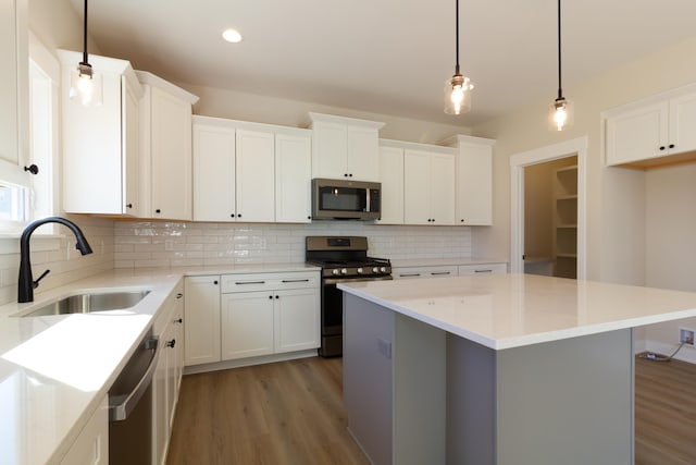 kitchen with hanging light fixtures, sink, white cabinets, and stainless steel appliances