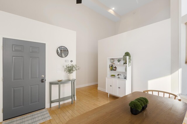 entryway featuring light wood-type flooring, a high ceiling, and beam ceiling