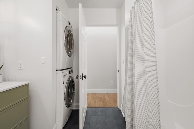 laundry room with stacked washer and clothes dryer and dark hardwood / wood-style floors