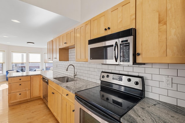 kitchen featuring light hardwood / wood-style floors, light stone counters, sink, light brown cabinets, and appliances with stainless steel finishes