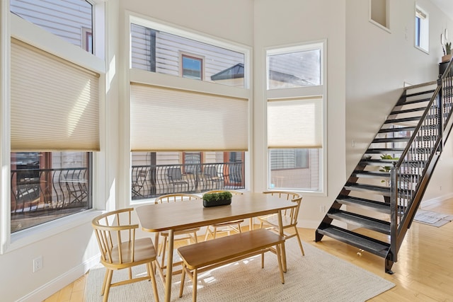 dining room featuring a towering ceiling and wood-type flooring