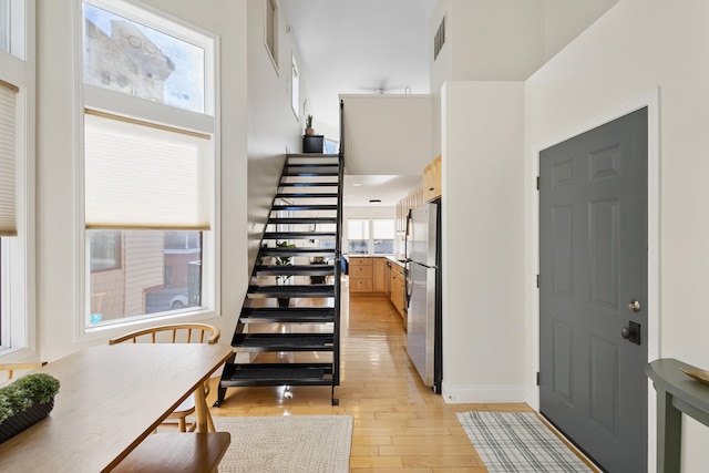 entryway with a towering ceiling and light hardwood / wood-style flooring