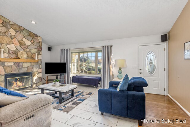 living room featuring light wood-type flooring, a stone fireplace, and lofted ceiling