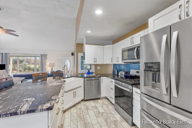 kitchen with ceiling fan, sink, dark stone countertops, white cabinets, and appliances with stainless steel finishes