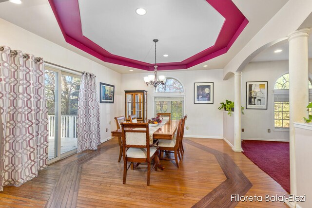 dining space with a tray ceiling, a chandelier, and a healthy amount of sunlight