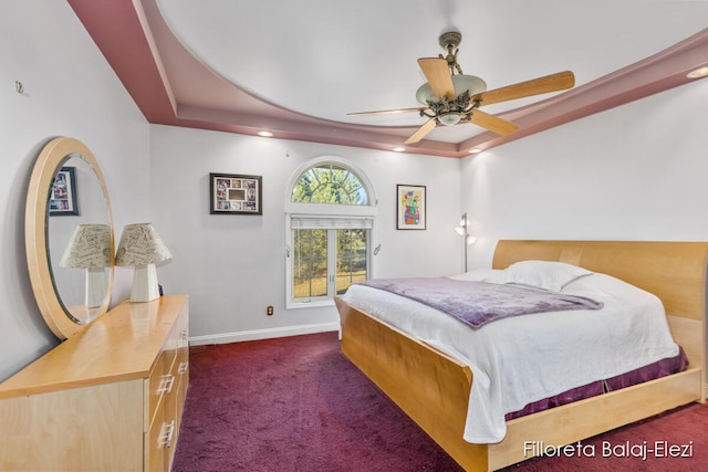 carpeted bedroom with a tray ceiling and ceiling fan