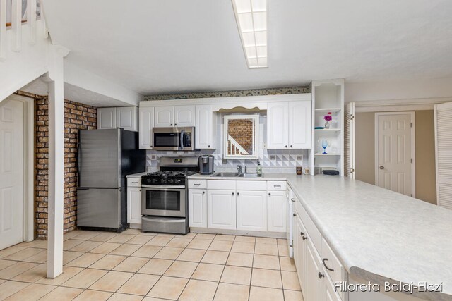 kitchen with appliances with stainless steel finishes, backsplash, sink, light tile patterned floors, and white cabinets