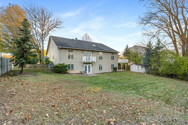 back of house with a lawn, a balcony, french doors, and a shed