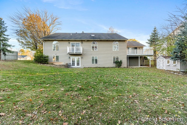 rear view of house with french doors, a yard, a storage unit, and a balcony