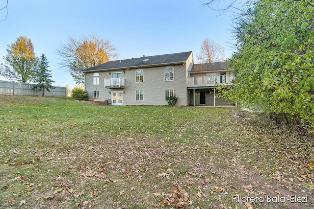 back of property with french doors, a lawn, a wooden deck, and a balcony