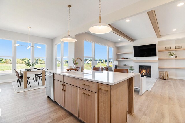 kitchen featuring pendant lighting, light brown cabinets, sink, an island with sink, and light hardwood / wood-style flooring