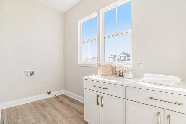 clothes washing area featuring cabinets, hookup for a washing machine, and light wood-type flooring